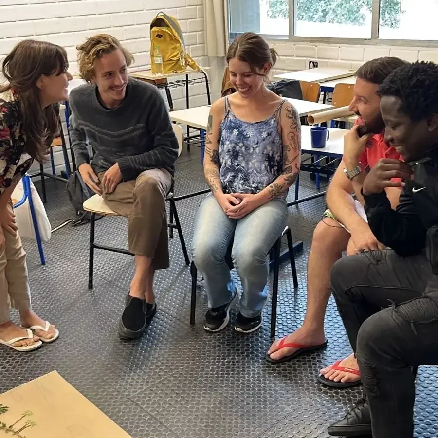 Estudantes sentados em roda conversam e riem numa sala de aula